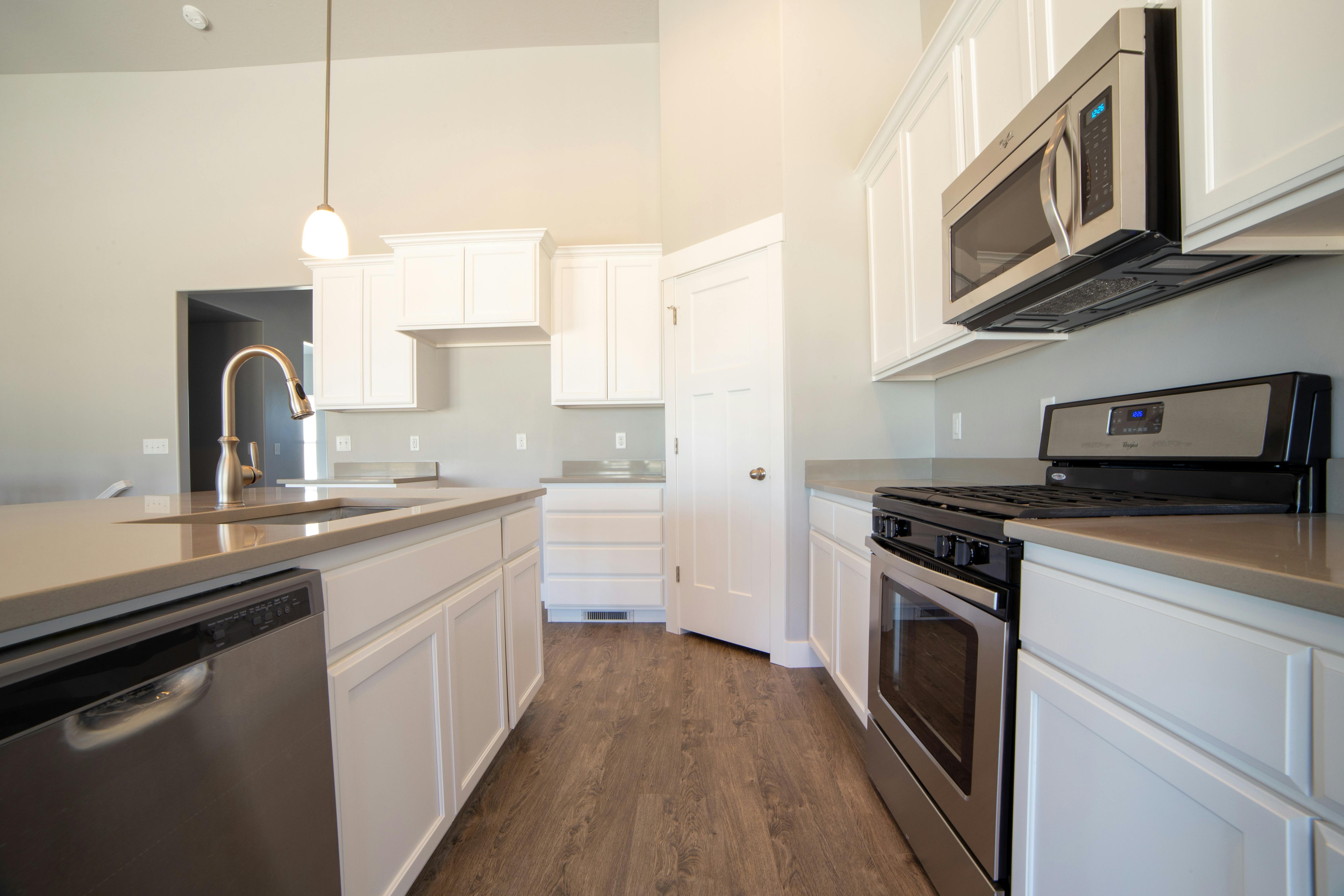 Service Spacious modern kitchen with white cabinets and stainless steel appliances.