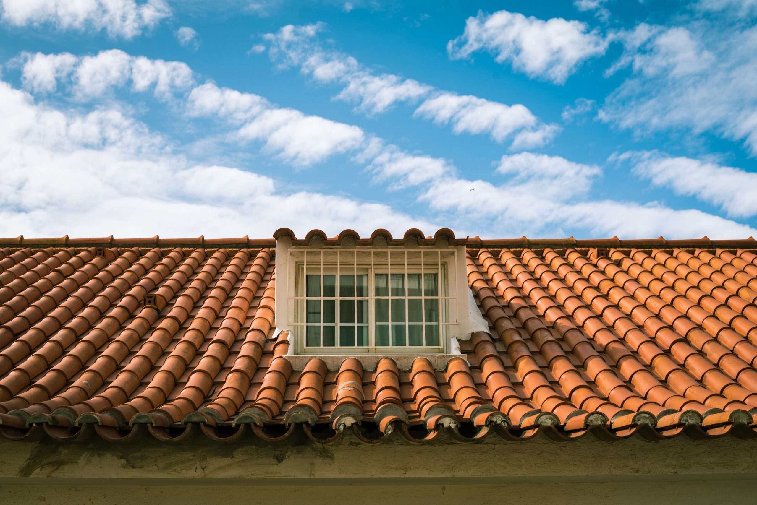 Service Close-up of a terracotta tiled roof with a skylight window in sunny Marbella, Spain.